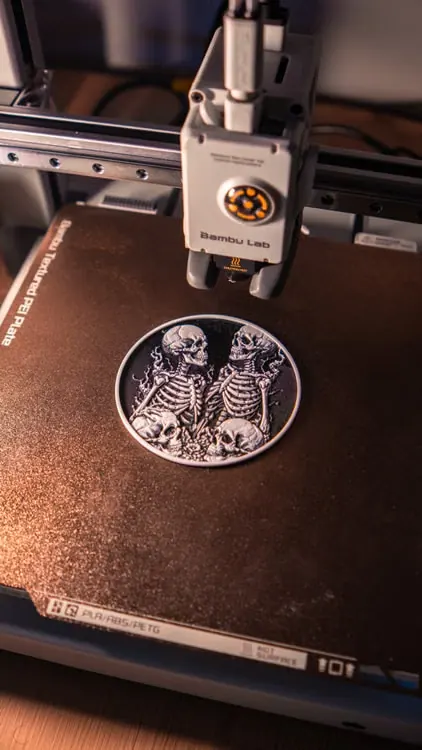 Impresora 3D FDM fabricando una pieza circular con relieve sobre cama texturizada